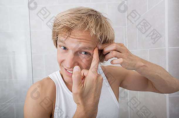 男人在浴室挤压额头上的丘疹的肖像