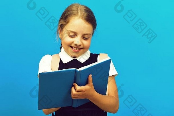 回到学校和教育理念。穿着校服的学生微笑着。这个女孩在做家庭作业时在蓝色的大<strong>本子</strong>上写字。脸上带着快乐的女学生，被隔离在蓝色<strong>背景</strong>上