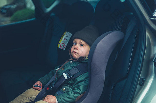 一个蹒跚学步的小孩坐在汽车的座位上等着开车离开