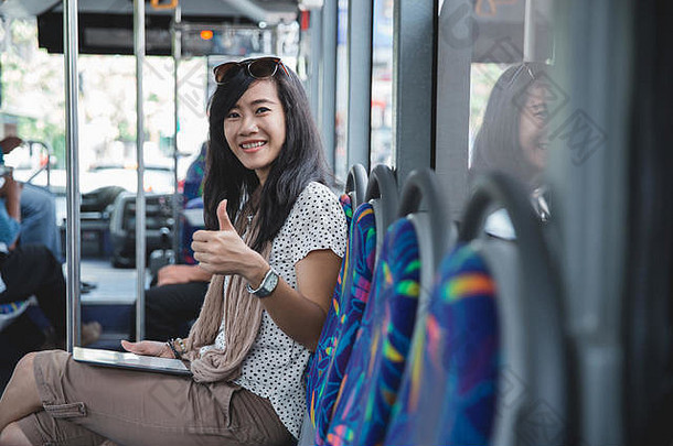 在<strong>公交车上</strong>使用数字平板电脑的女士用拇指看相机