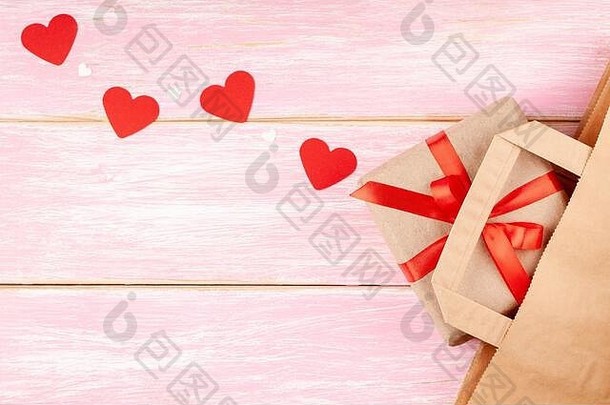 手工纸袋和礼品盒，红色丝带蝴蝶结和心形，粉色背景