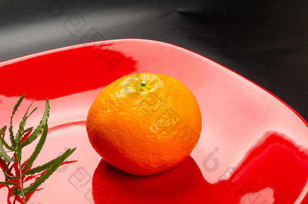 红色盘子里的<strong>橘子</strong>，黑色背景