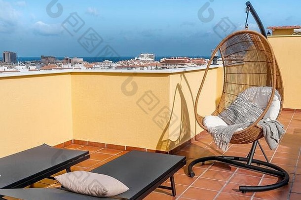在阳光明媚的露台上悬挂着椅子和太阳床，这是一个可以欣赏海景的休闲度假胜地。