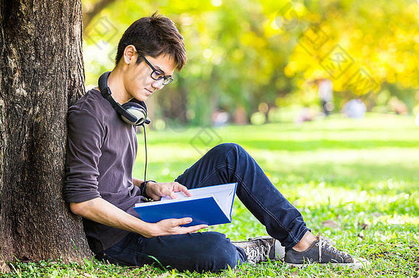 聪明的学生读教科书放松听音乐耳机公园曼谷泰国亚洲
