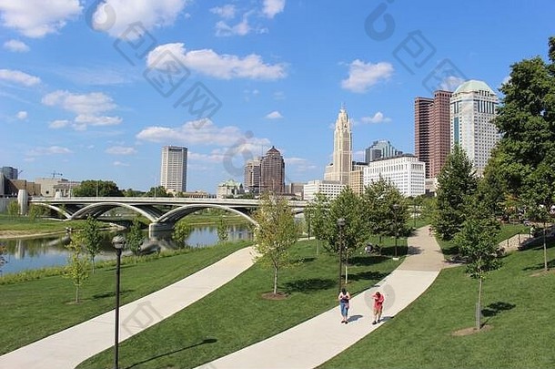亚历山大公园俄亥俄州哥伦布市<strong>中心绿地</strong>景观，绿树成荫，水泥人行道，五颜六色的树木，城市的天际线结构，蔚蓝的天空