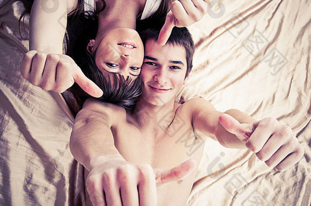 一对幸福的夫妇竖起大拇指躺在床上