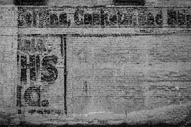 一堵旧的油漆过的废弃仓库砖墙。涂上不可读的字母看起来非常古老和风化。