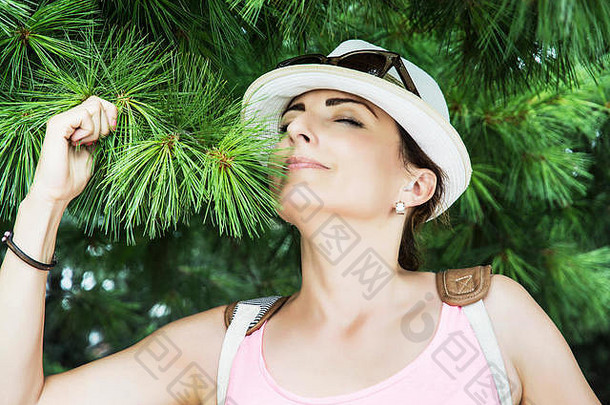 一位年轻的白人妇女在公园里嗅着<strong>针</strong>叶树的绿色<strong>针</strong>叶。自然美。积极的情绪。