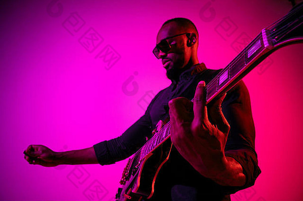 年轻的非裔美国人<strong>音乐</strong>家玩吉他明星梯度purple-pink背景霓虹灯光概念<strong>音乐</strong>爱好快乐的有吸引力的的家伙即兴创作色彩斑斓的肖像