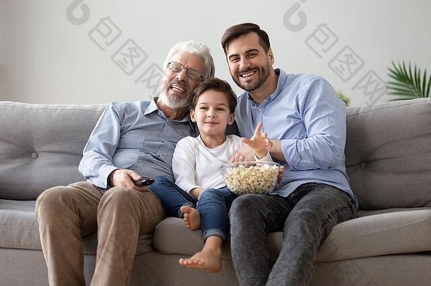 快乐的祖父大人的儿子和孙子看电视吃爆米花