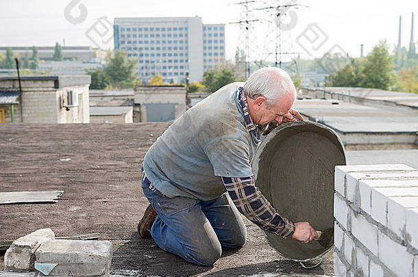 岁的首页盖屋顶的人准备砂浆盆地修复屋顶的水泥冗长的防水纸