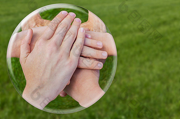 双手联合在绿草上隔离的玻璃球中