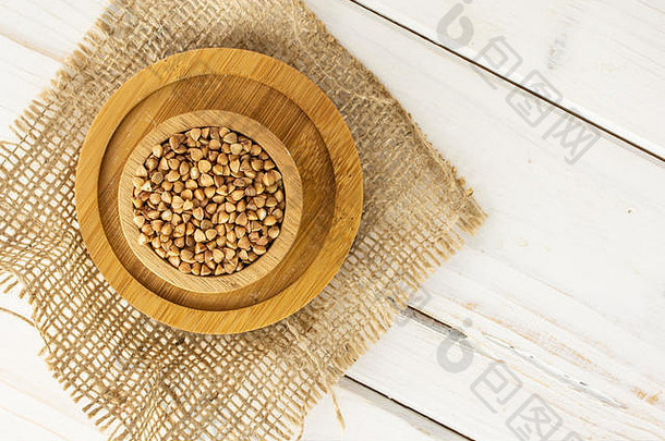 将整粒生的棕色<strong>荞麦</strong>粒放在木碗里，放在黄麻布上，放在竹板上，平铺在白木上