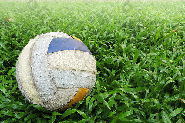 绿色草地上的旧足球，光线柔和。，足球激情与空间背景。
