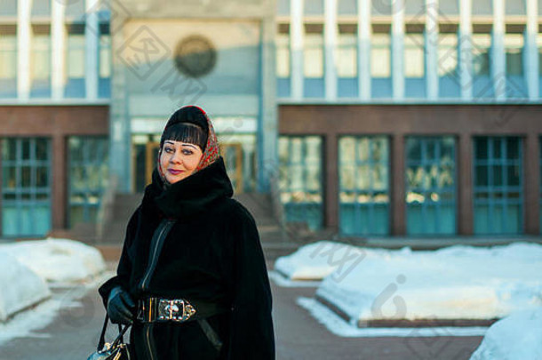 <strong>冬季</strong>城市环境中一位穿着<strong>保暖</strong>服装、戴着传统头巾的成年妇女的肖像