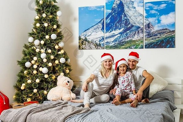 戴着<strong>圣诞</strong>帽的一家人，婴儿妈妈和爸爸，三个人在白色背景下看着相机