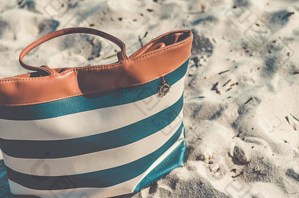 把袋子盖在沙滩上的沙子上。旅游袋