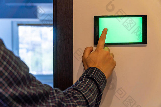 智能家居控制和安全概念。墙上挂着空白屏幕的设备，人们用手指按下按钮。