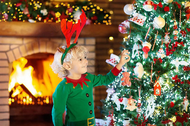 圣诞前夜，孩子们在圣诞树和壁炉旁。一家人带着孩子在家庆祝圣诞节。小男孩在装饰圣诞树和圣诞礼物