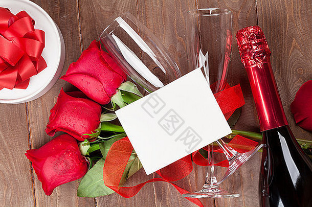 情人节贺卡，香槟和红<strong>玫瑰</strong>放在木桌上。具有空间的俯视图