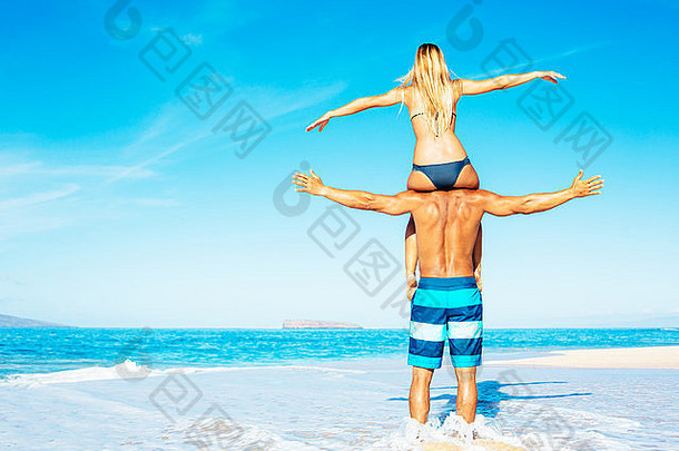 一对美貌的夫妇在美丽的阳光海滩上玩得很开心