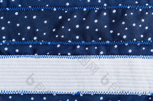 织物背景由蓝色织物制成，带有白点、锯齿形缝线和白布条纹。