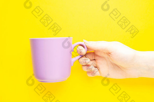黄色背景上手持咖啡杯的创意概念照片。