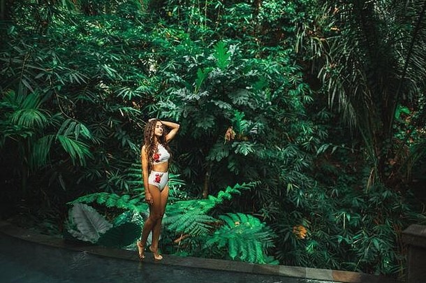 美丽的苗条的浅黑肤色的女人女人白色<strong>泳衣</strong>边缘奢侈品游泳池在户外丛林巴厘岛