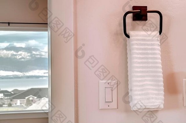 白色毛巾挂在电动摇杆灯开关旁边的方形毛巾架上