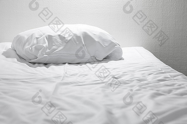 一个白色的枕头躺在空床上