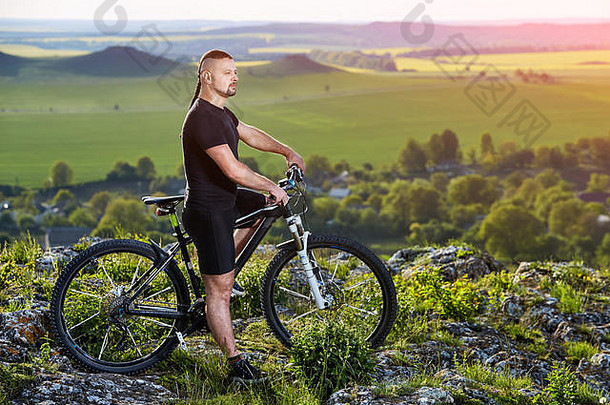 骑自行车的人和山地车站在美丽的风景背景下。