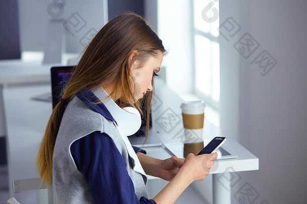 戴着耳机的专注专注的女人坐在桌旁，拿着笔记本电脑，看着屏幕，做笔记，在互联网上学习外语