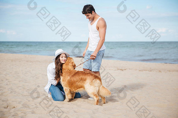浪漫的年轻美丽的夫妇带着狗在海边散步
