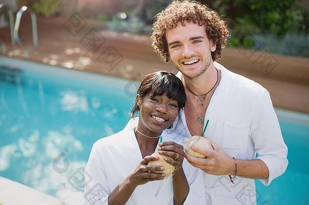 一对穿着浴衣、在池边喝椰子汁的快乐年轻夫妇