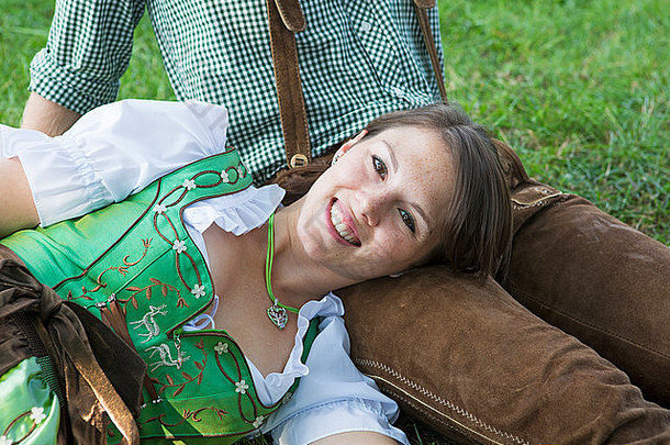 夫妇传统的巴伐利亚衣服坐着草