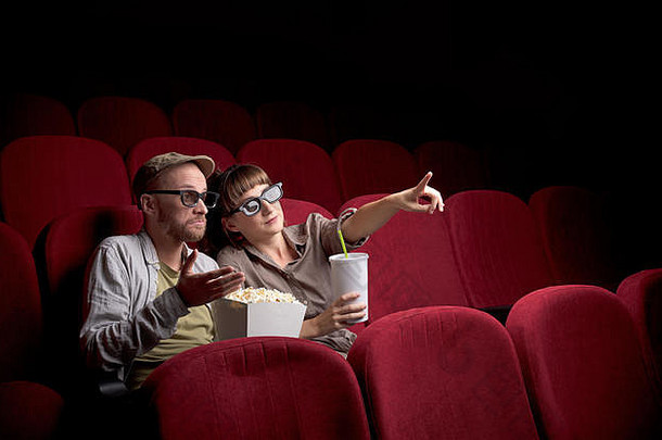 一对年轻可爱的夫妇独自坐在红色电影院里玩得很开心