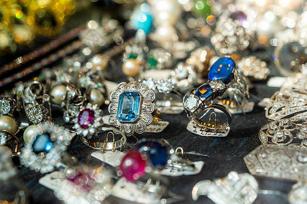 散焦视角下的珠宝店，多枚戒指和耳环，蓝色洋红宝石和半宝石待售，如西班牙时装展示店所示