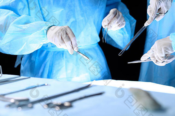执行手术的医疗队。一组外科医生正在手术室工作，蓝色调