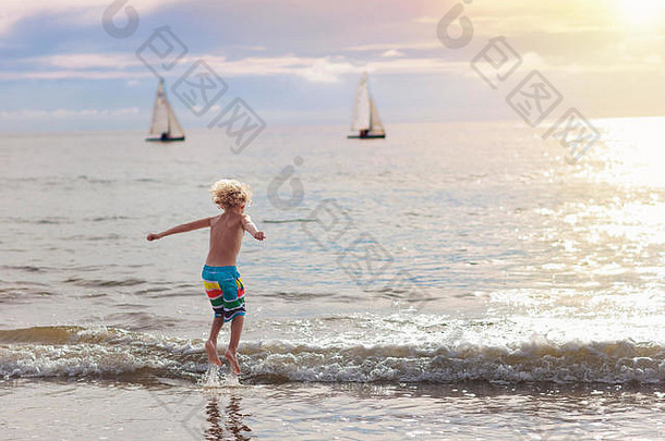 孩子们在海边玩耍。日落时，孩子在波浪中跳跃。带孩子的家庭海上度假。在异国情调的热带海滩上奔跑的小男孩