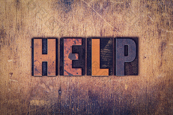 “帮助”这个词是在一个陈旧的木制背景上用肮脏的老式活版印刷字体写的。