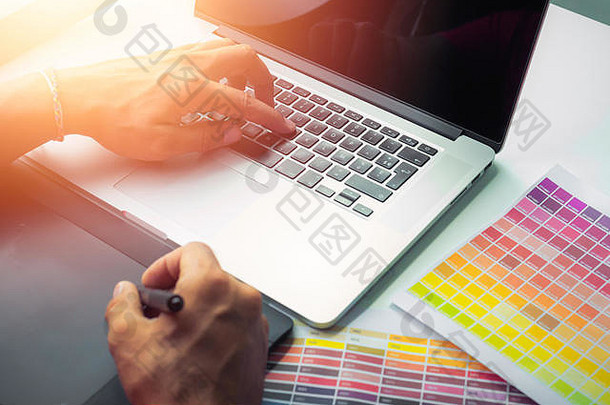 设计师手工操作新型现代笔记本电脑和pro digital平板电脑，并在白色桌面上放置样品色板