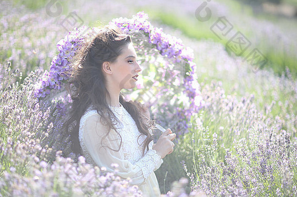 美丽的年轻的女孩在户外薰衣草花场