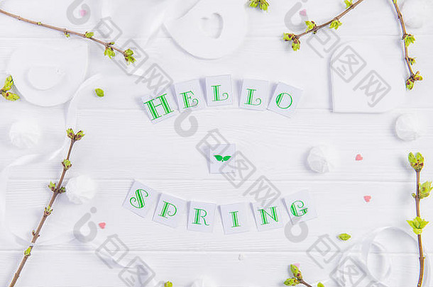 顶视图构图：Hello spring字样、嫩枝绿叶、梅伦格糖果和糖果心形、手工制作的鸟形图案