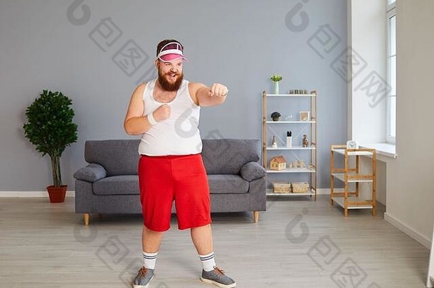 穿着运动服的滑稽胖拳击手正在房间里打拳击。