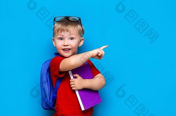 回到学校一年级<strong>初中</strong>生活方式。穿红色t恤的小男孩。摄影棚特写照片：戴眼镜的微笑男孩，带着书包和相机