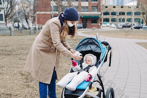 多伦多，一位年轻的白人母亲给婴儿戴上了外科口罩。防护口罩预防中国<strong>新</strong>非典型<strong>肺炎新冠</strong>病毒-1