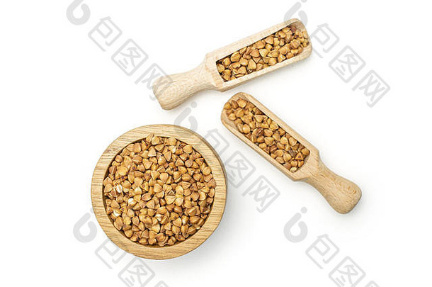 在一个木碗中放入大量全壳生的棕色<strong>荞麦</strong>粒，在白色背景上用木勺隔开