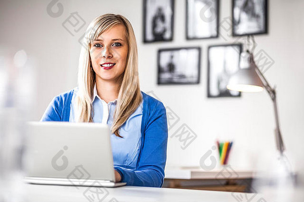 美丽的年轻女商人在办公室使用笔记本电脑的肖像