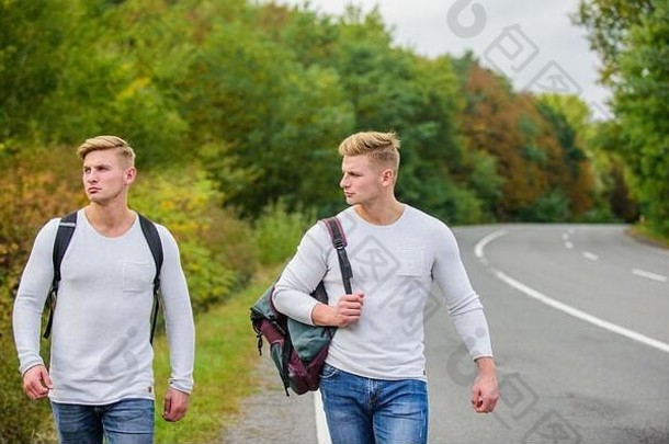 <strong>暑假</strong>旅游者旅游自动停止。廉<strong>价</strong>旅行者。男人们背着背包一起走在路边。一对双胞胎沿着路走。冒险与发现。背着背包的男人在路上搭便车。