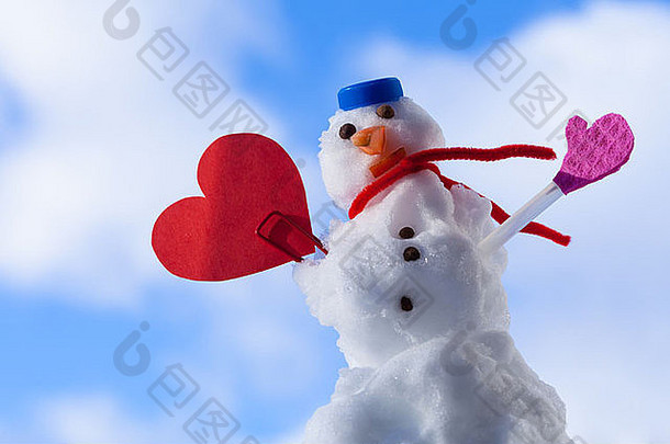 冬天有趣的情人节雪人，纸红色心形情人节的爱情象征。蓝天背景。户外的